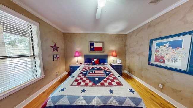 Main house second bedroom with wood flooring, baseboards, crown molding, and ceiling fan | Image 17
