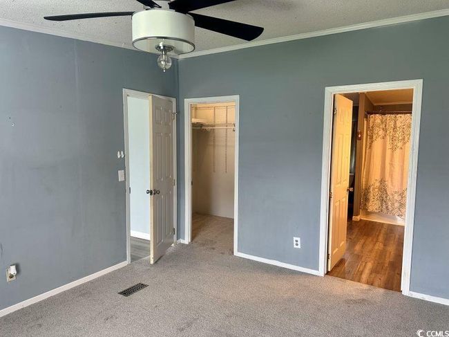 Unfurnished bedroom with crown molding, new carpet flooring, a spacious closet, a closet, and baseboards | Image 16