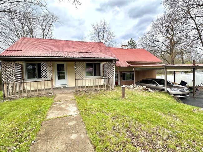 View of front of home featuring a porch, an attached carport, a front yard, and metal roof | Image 45