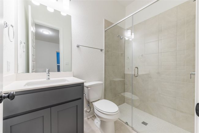 Bathroom with a stall shower, vanity, and a textured wall | Image 11