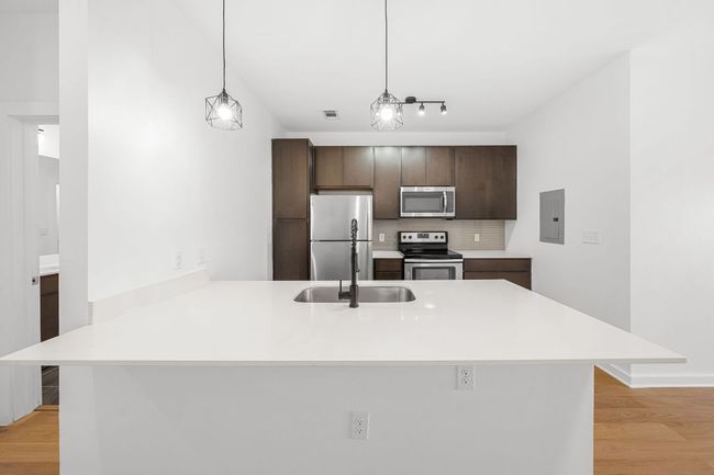 Kitchen featuring tasteful backsplash, electric panel, light wood-style flooring, a peninsula, and stainless steel appliances | Image 5