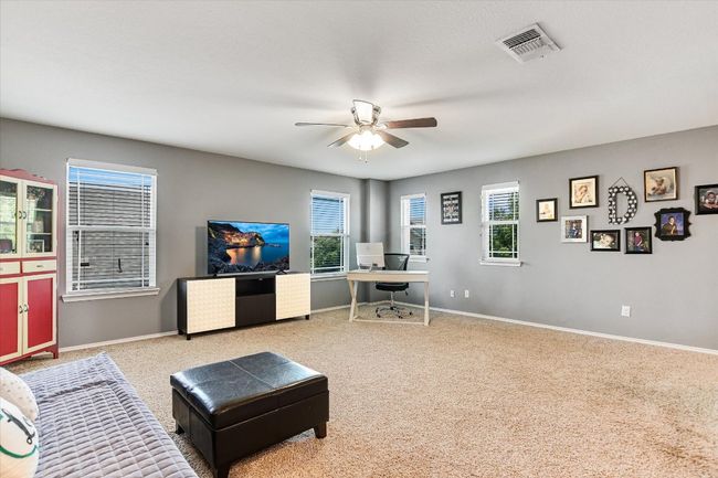 Carpeted living area with a desk, a ceiling fan, plenty of natural light, and baseboards | Image 19
