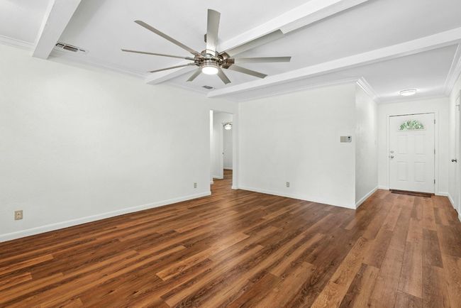 Spare room featuring ornamental molding, dark wood-type flooring, ceiling fan, and beam ceiling | Image 4