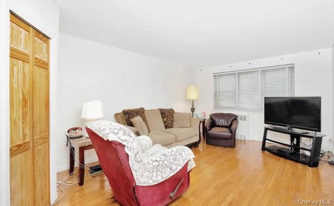 Living area with wood finished floors and radiator heating unit | Image 9