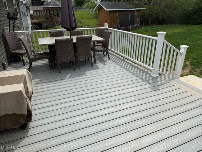 Wooden deck featuring a yard, outdoor dining space, a shed, an outbuilding, and a trampoline | Image 19
