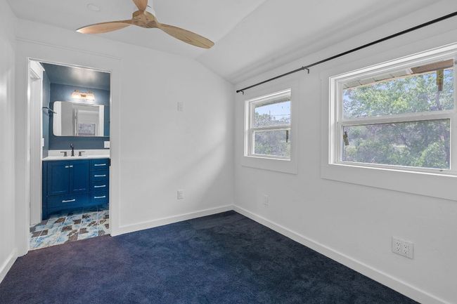 Unfurnished bedroom with lofted ceiling, dark colored carpet, ensuite bath, and a ceiling fan | Image 16