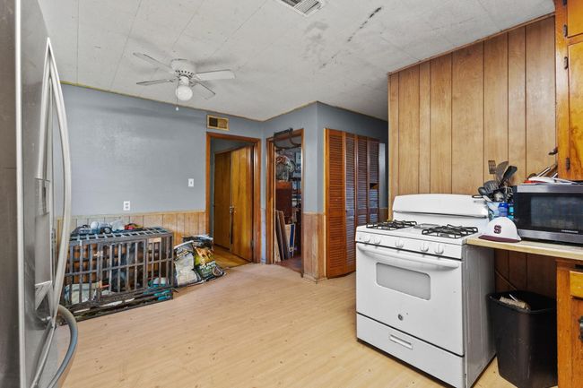 Kitchen featuring appliances with stainless steel finishes, light wood-style floors, wood walls, a ceiling fan, and a wainscoted wall | Image 8