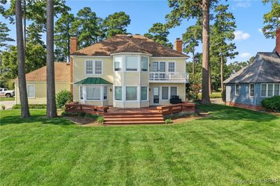 Rear view of property overlooking river with a wooden deck, lawn, and balcony | Image 2