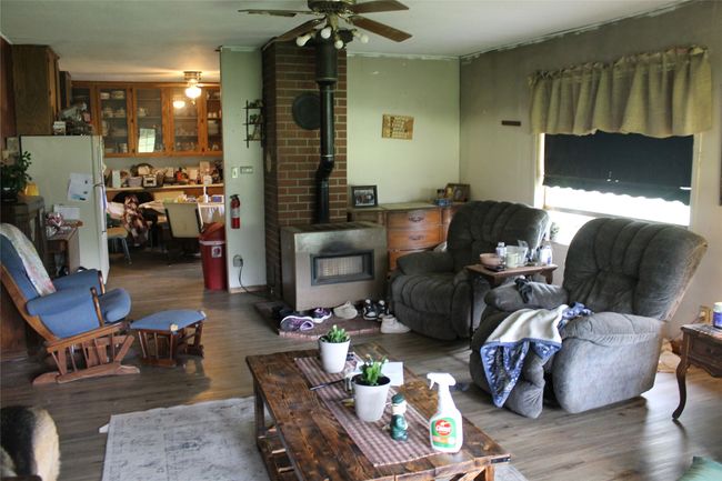 Living area featuring a wood stove, ceiling fan, and wood finished floors | Image 19