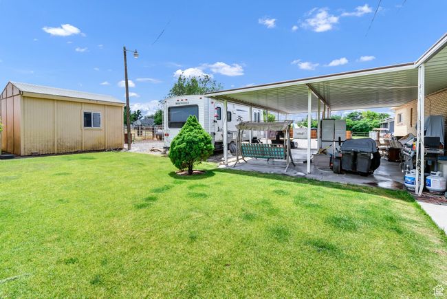 View of green lawn featuring a patio area, an outdoor structure, a pergola, and a carport | Image 25