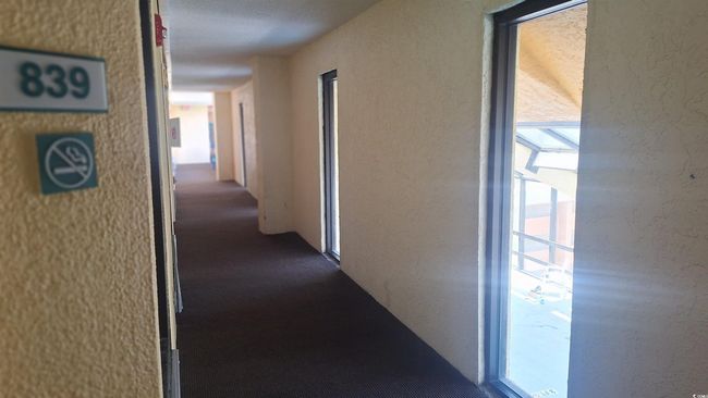 Hall with dark colored carpet and a textured wall | Image 16
