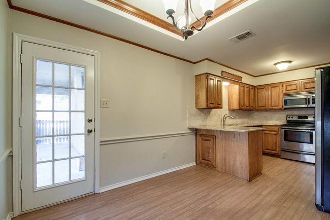 Kitchen with stainless steel appliances, a chandelier, light wood-style flooring, backsplash, and crown molding | Image 15