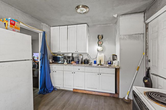 Kitchen with freestanding refrigerator, stainless steel microwave, white cabinetry, and dark wood-type flooring | Image 5