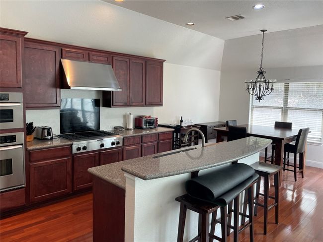 Kitchen with stainless steel gas stovetop, under cabinet range hood, and sink. | Image 10