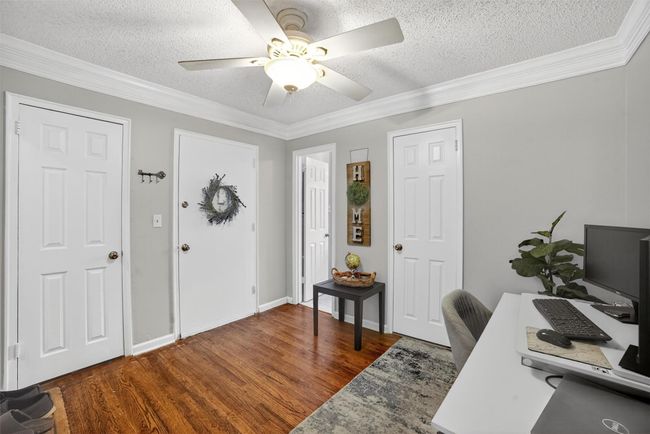 Office space with wood finished floors, a textured ceiling, ceiling fan, and ornamental molding | Image 6