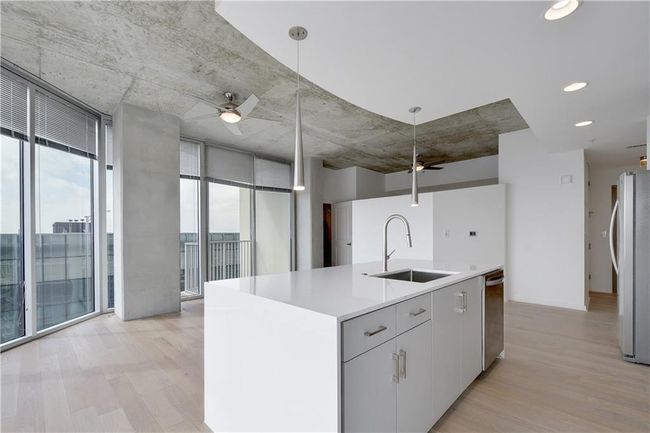 Kitchen with a sink, stainless steel appliances, a ceiling fan, and a wall of windows | Image 7