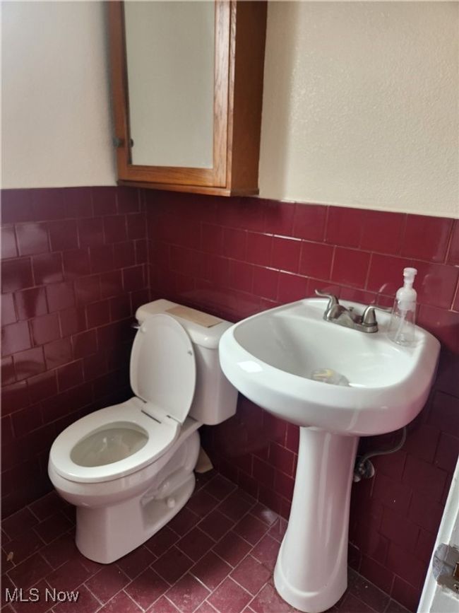 Bathroom with toilet, tile patterned floors, and tile walls | Image 8