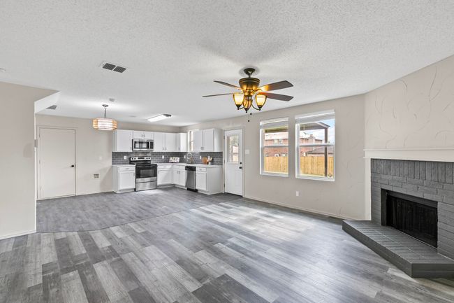 Kitchen featuring stainless steel appliances, light countertops, wood finished floors, white cabinetry, and a ceiling fan | Image 6