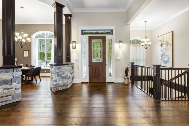 Foyer entrance with decorative columns, baseboards, dark wood-style flooring, an inviting chandelier, and crown molding | Image 5