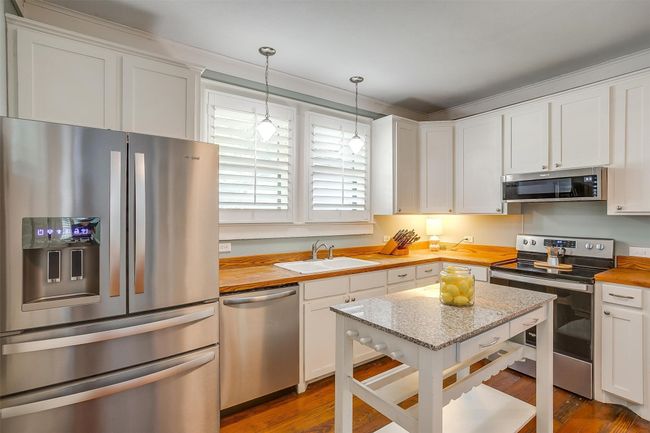 Kitchen with appliances with stainless steel finishes, butcher block counters, white cabinets, and wood finished floors | Image 24