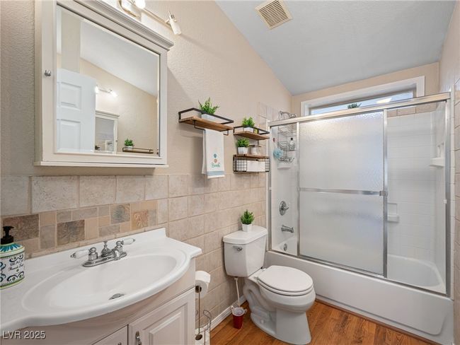 Full bath with visible vents, toilet, wood finished floors, tile walls, and enclosed tub / shower combo | Image 40