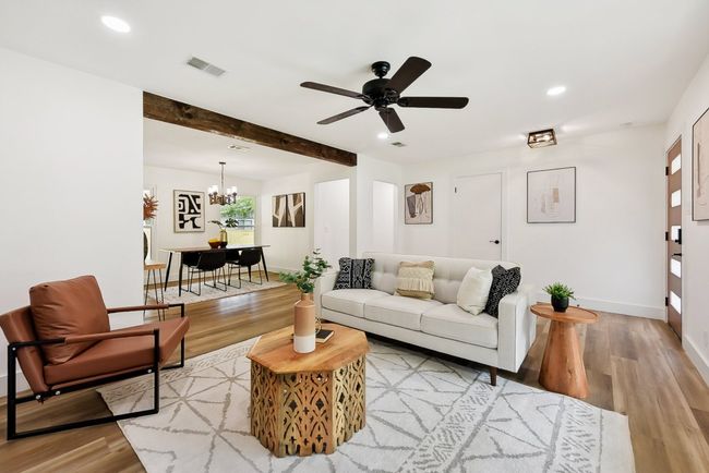 Living room with beamed ceiling, ceiling fan with notable chandelier, visible vents, and light wood-type flooring | Image 4