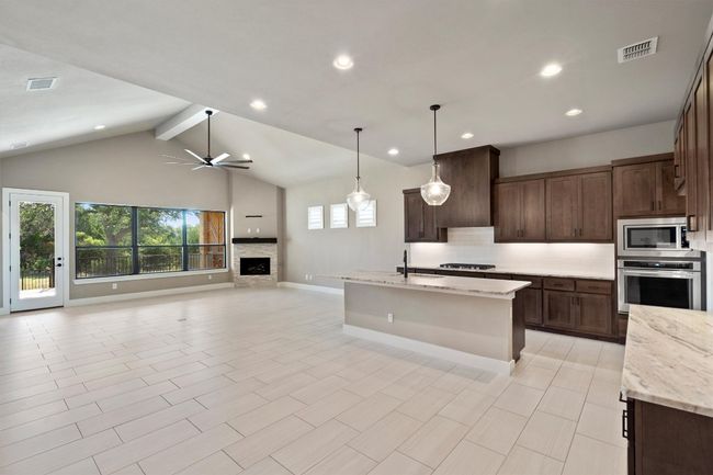 Kitchen featuring appliances with stainless steel finishes, decorative backsplash, ceiling fan, open floor plan, and dark brown cabinets | Image 4