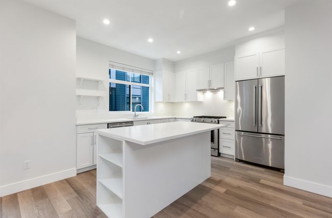 Kitchen with open shelves, light countertops, white cabinetry, and stainless steel appliances | Image 8