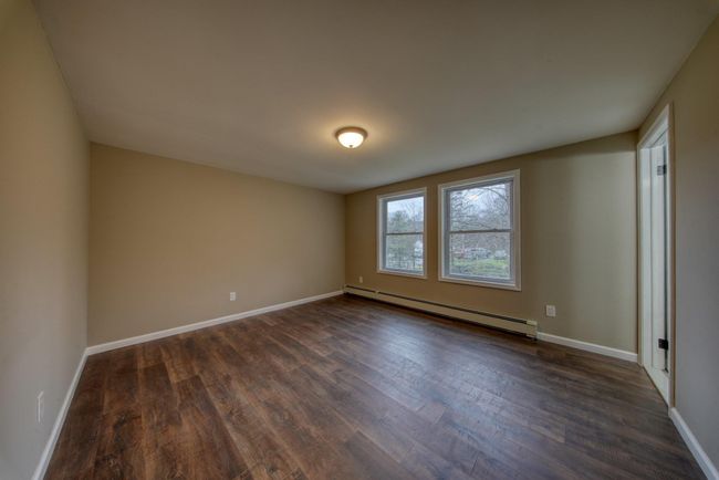 Spare room with baseboards, dark wood-style floors, and a baseboard radiator | Image 14