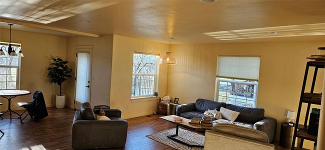 Living room featuring an inviting chandelier, wood finished floors, and baseboards | Image 4