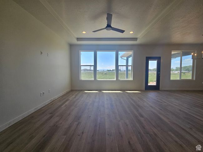 Unfurnished living room with dark wood-style flooring, healthy amount of natural light, baseboards, a textured ceiling, and a tray ceiling | Image 10
