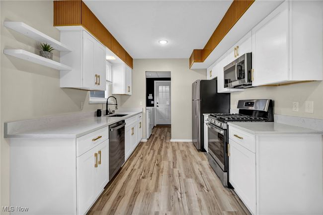 Kitchen featuring appliances with stainless steel finishes, separate washer and dryer, white cabinetry, and recessed lighting | Image 9