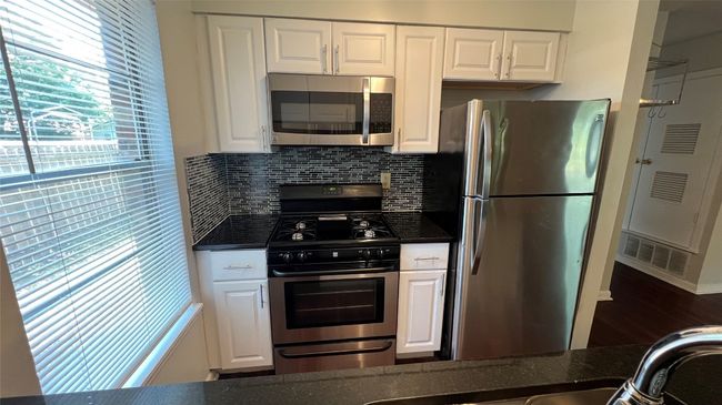 Kitchen with appliances with stainless steel finishes, white cabinets, tasteful backsplash, and wood finished floors | Image 5