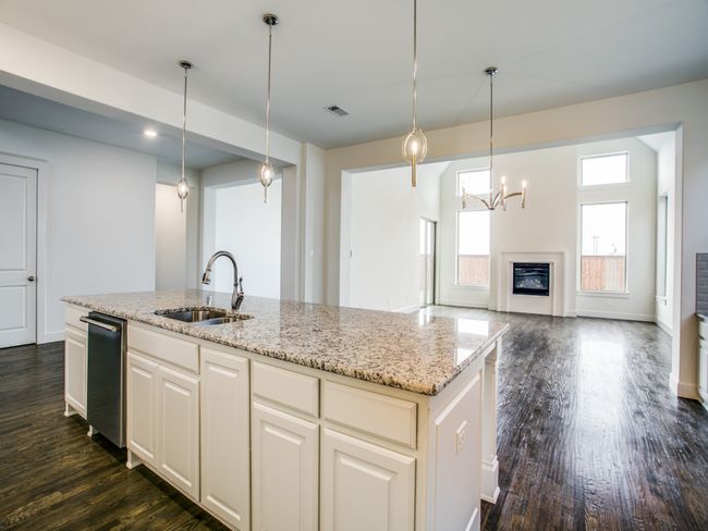 Kitchen featuring dark wood finished floors, light stone countertops, and an island with sink | Image 11