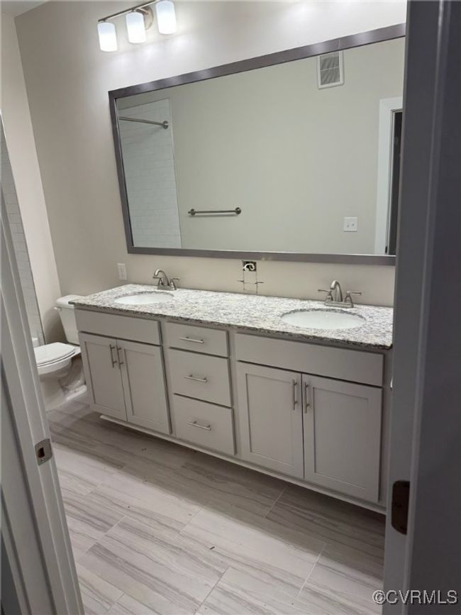 Bathroom featuring a sink, visible vents, toilet, and double vanity | Image 19