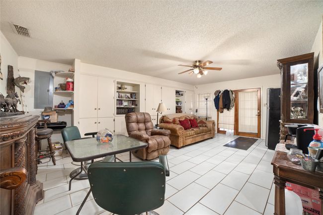 Living room featuring ceiling fan, light tile patterned floors, electric panel, and a textured ceiling | Image 9