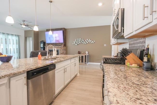 Kitchen with a ceiling fan, a sink, appliances with stainless steel finishes, white cabinetry, and light wood-type flooring | Image 9