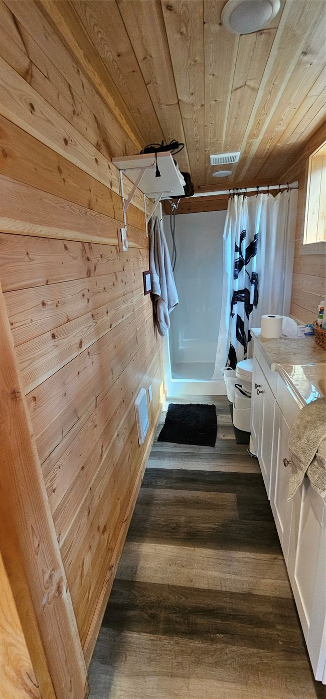 Bathroom featuring wooden walls, toilet, curtained shower, wood ceiling, and vanity | Image 13