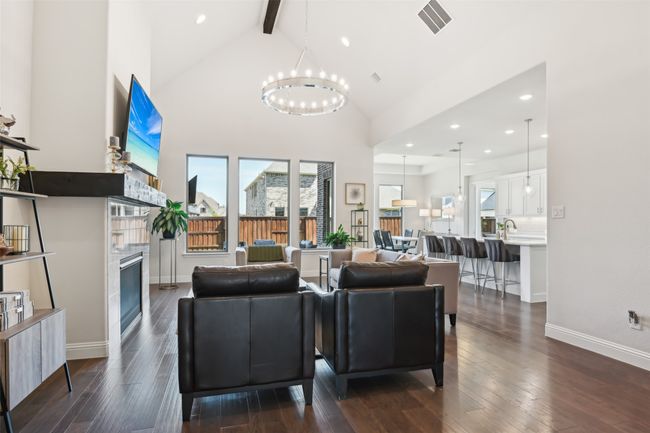 Living room with a glass covered fireplace, beamed ceiling, a chandelier, dark wood-style flooring, and high vaulted ceiling | Image 9