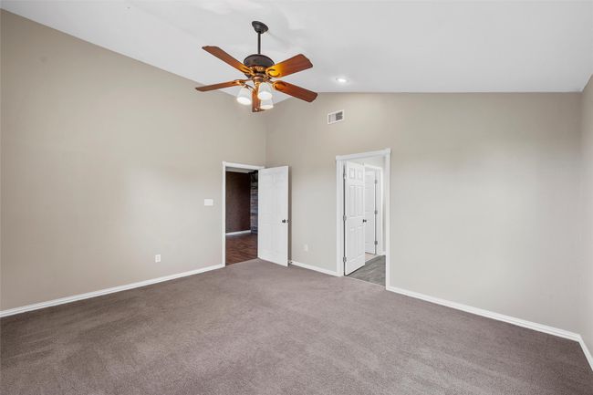 Unfurnished bedroom with dark colored carpet, high vaulted ceiling, and a ceiling fan | Image 16