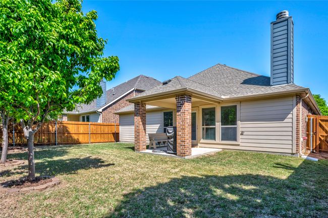 Rear view of property featuring a fenced backyard, a lawn, roof with shingles, a patio area, and brick siding | Image 36