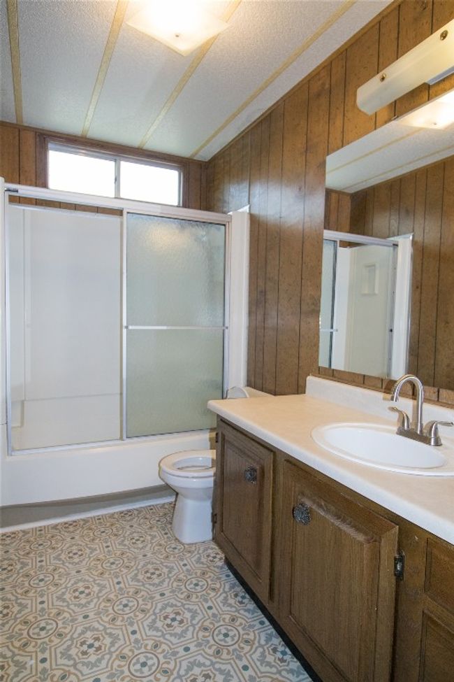 Full bath with wood walls, vanity, and bath / shower combo with glass door | Image 14