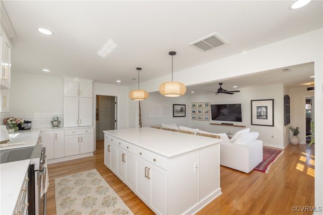 Kitchen featuring light wood finished floors, a kitchen island, visible vents, and gas stove | Image 9