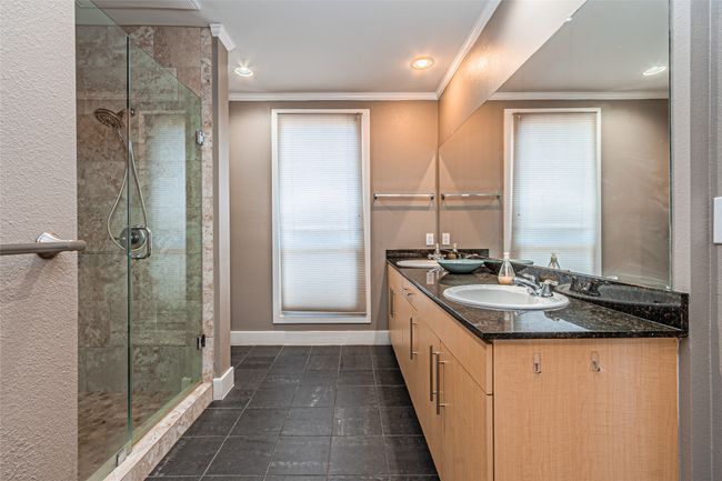 Bathroom featuring double vanity, a shower stall, ornamental molding, and tile patterned floors | Image 25