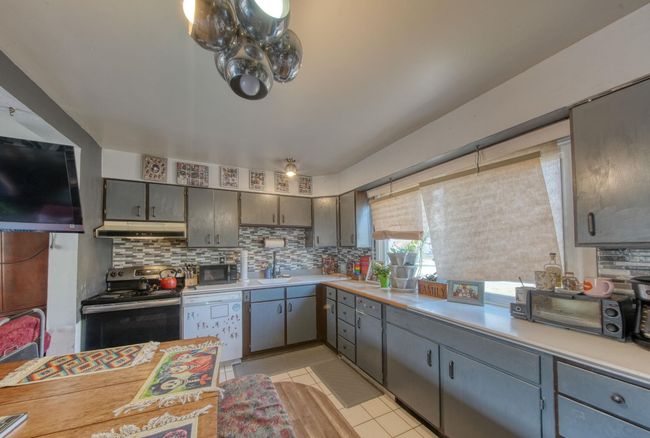 Kitchen featuring dishwasher, stainless steel electric stove, under cabinet range hood, and tasteful backsplash | Image 9