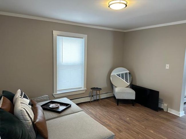 Sitting room with ornamental molding, wood-type flooring, and a baseboard heating unit | Image 4
