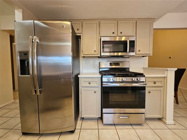 Kitchen with appliances with stainless steel finishes, light tile patterned floors, and light countertops | Image 9