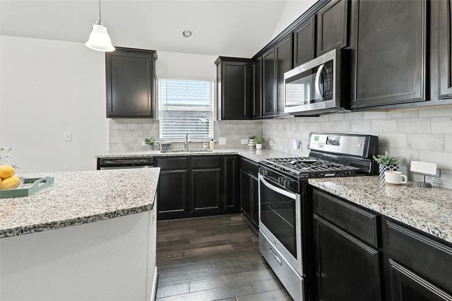 Kitchen with appliances with stainless steel finishes, dark wood-style flooring, tasteful backsplash, light stone countertops, and recessed lighting | Image 14