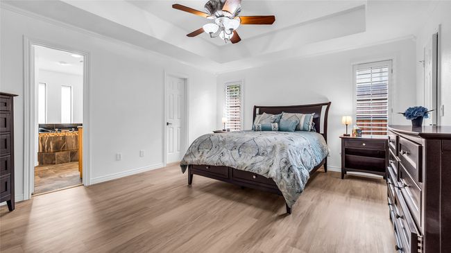 Bedroom with a tray ceiling, light wood-style flooring, and ceiling fan | Image 15