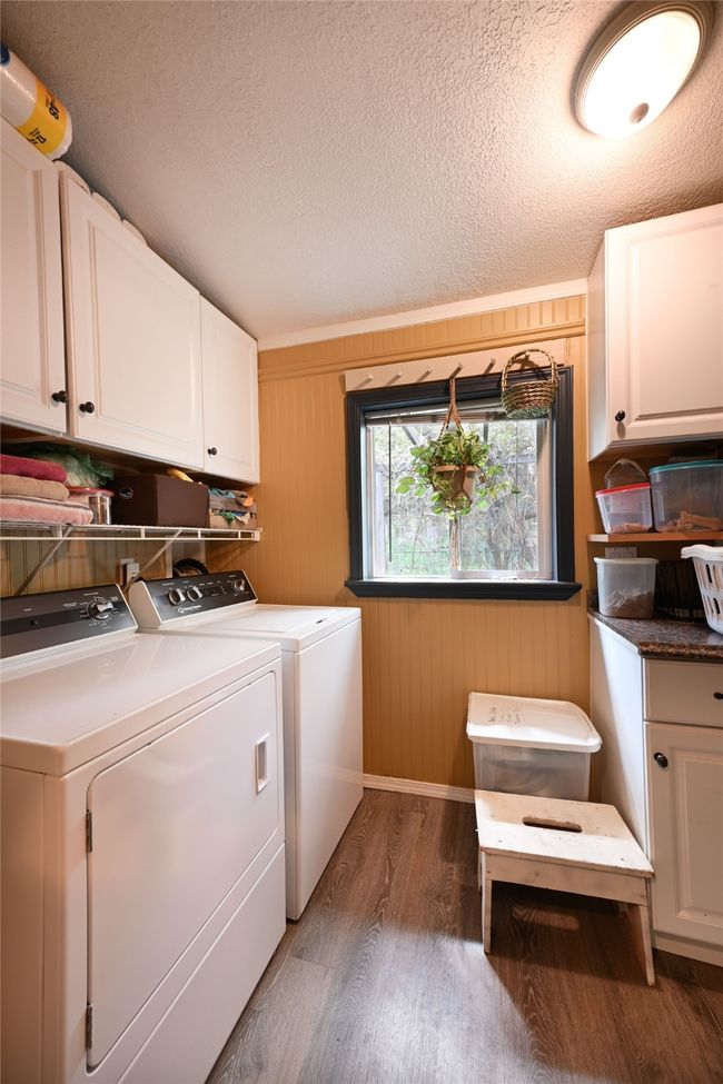 Laundry area featuring cabinet space, washer and clothes dryer, light wood-style floors, and a textured ceiling | Image 28